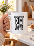 A DAY WITHOUT KIM IS A DAY WASTED mug handheld-white AI final 1350x1800